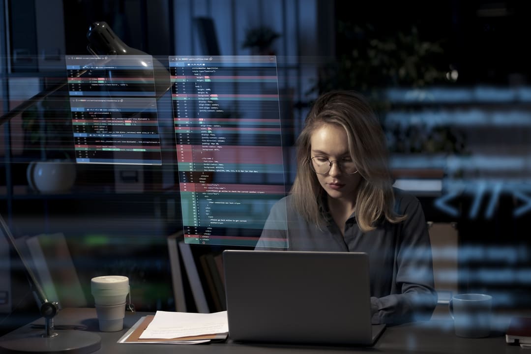 Mulher usando laptop à noite em ambiente de trabalho, com códigos flutuantes ao seu redor, simbolizando o processo de migração de dados e análise tecnológica.