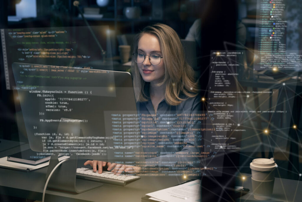 Mulher em escritório digitando em computador com códigos projetados, representando outsourcing de TI.