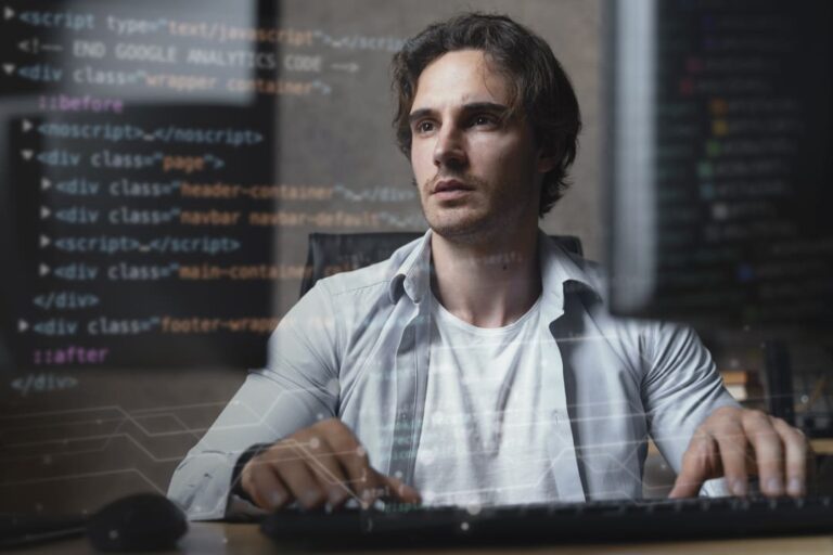 Homem concentrado trabalhando em um computador, com códigos de programação projetados sobre a imagem.